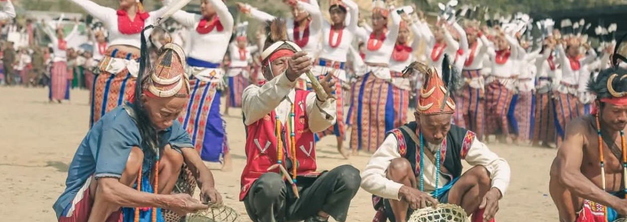 Wancho elders drumming as women in striped wraps dance in formation at the Oriah Festival, Longding District, Arunachal Pradesh