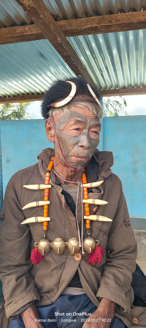 Tattooed Konyak elder at Longwa village, Mon district, wearing boar-tusk necklaces and brass head pendants