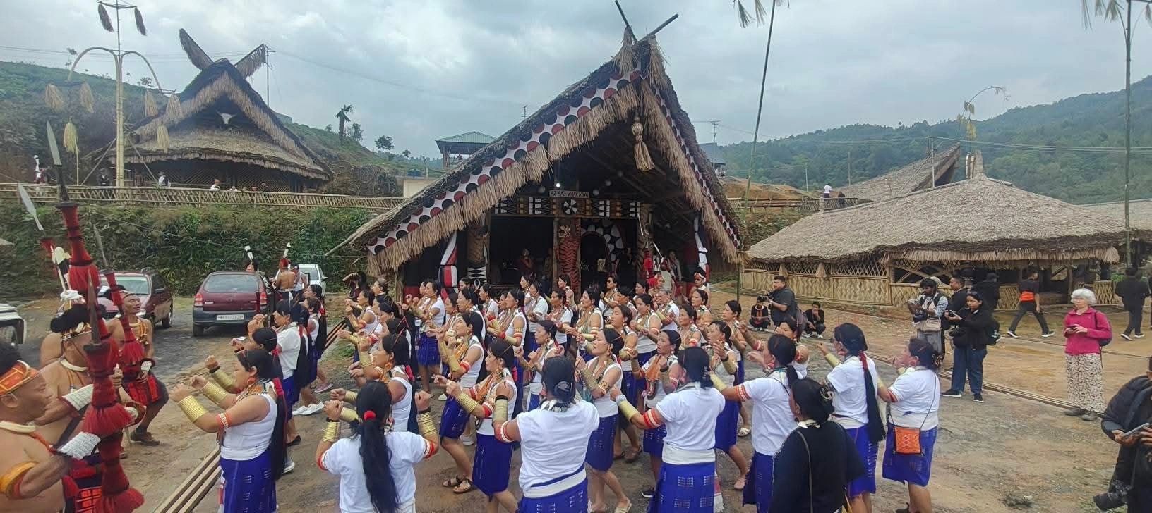 Crowd of Konyak villagers and visitors gathered in front of a large thatched morung with painted gable during Aoleang Festival in Mon, Nagaland