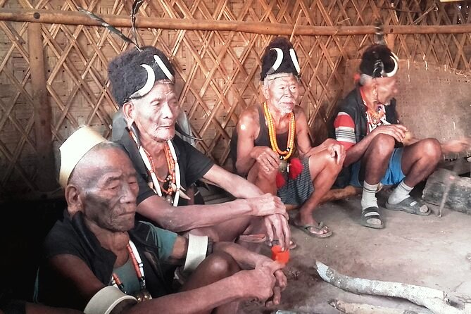 Konyak elders with headhunter hats and brass head pendants sitting inside a bamboo-walled house in Mon district